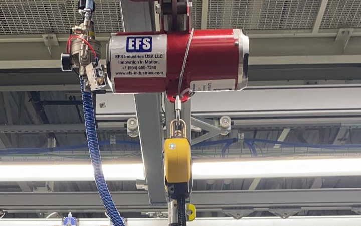 An EFS pneumatic balancer mounted on an overhead rail, with its pull cable and pulley below