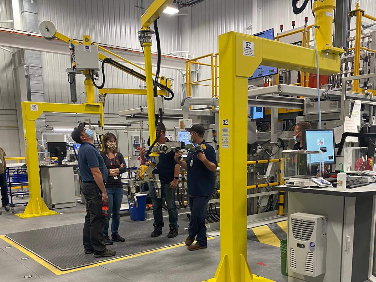 Engineers and technicians at a pair of EFS jib crane manipulators on a production floor