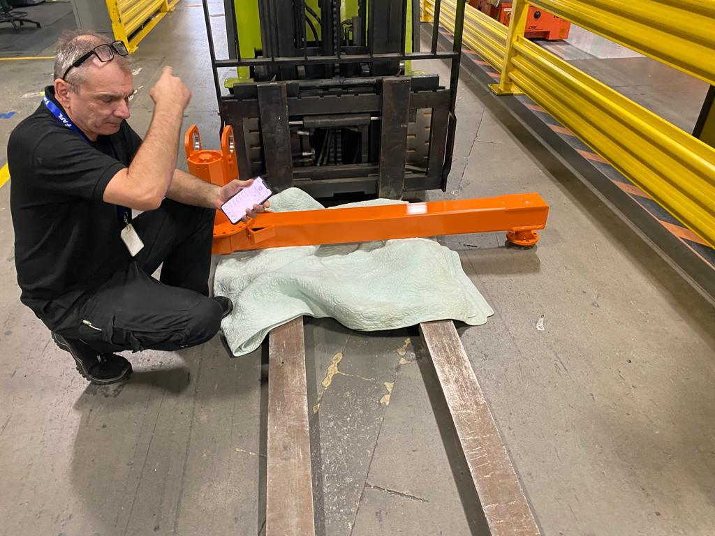 An EFS technician working on an orange lifting beam on the shop floor
